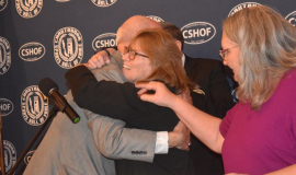 2024 inductee Karen Tellinghuisen hugs CSHOF president Randy Anderson. At right is American Sign Language interpreter Janelle Krueger.