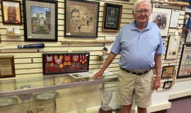 Dick Cole standing in front of a display case of his most prized golf trophies.