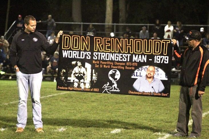 Fredonia Athletic Director Greg Lauer, left, and longtime coach Alex Conti, right, display a banner to honor Don Reinhoudt.