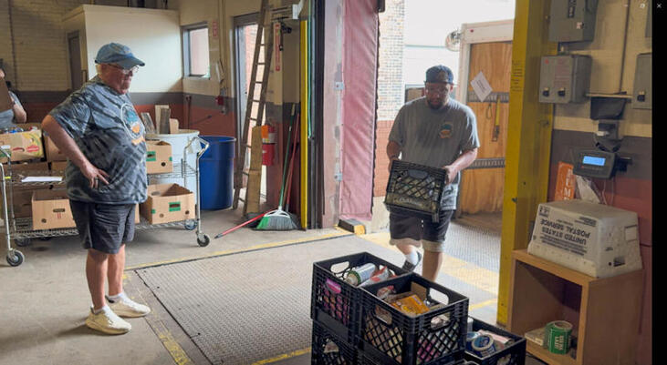Bob Goold, left, watches son Greg unload items from a truck. 