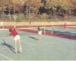 Nelson Turnell, in the second court wearing long, white pants, is giving a tennis lesson. In the near court are four Turnell pupils playing a match. Tim Johnson, in red shirt, Nelson's grandson, and his playing partner Judy Calanni are hitting to Don Bube and another Turnell grandson, Brett Johnson.
Photo courtesy of Dan Turnell. Photograph of several players on tennis court under tutelage of Nelson Turnell.