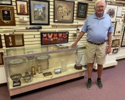 Dick Cole standing in front of a display case of his most prized golf trophies at the CSHOF on July 26, 2022. Dick Cole standing in front of a display case of his most prized golf trophies.