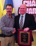 Former NASCAR driver Ernie Irvin congratulates Dick Barton on receiving the Top Gun Award at the Stateline Speedway banquet January 17, 2015. Barton retired as the all-time late model feature winner in the history of Stateline Speedway.