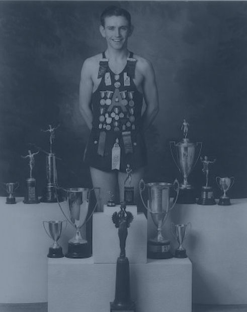 Brad Rendell standing with a collection of trophies and awards he earned.