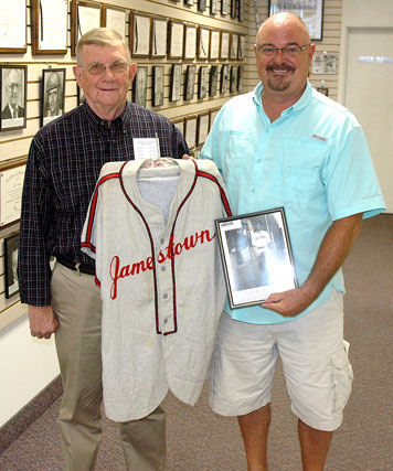 Chautauqua Sports Hall of Fame board member Russ Ecklund, left, accepts from Ted Wyberanec a jersey his father wore as a member of the Jamestown Merchants.