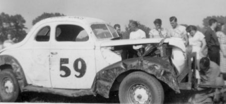 Dunkirk, NY, 1950. Lloyd Moore, second,from left, near the windshield, wearing a t-shirt, with his head turned. Julian Buesink is in front of the car adjusting the tow bar.