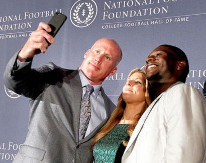 Shane Conlan, left, and former TCU tailback LaDainian Tomlinson, right, pose for a selfie with event emcee Bonnie Bernstein.