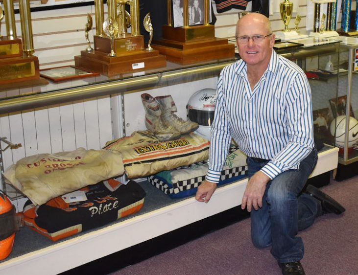 Dick Barton poses in front of memorabilia.