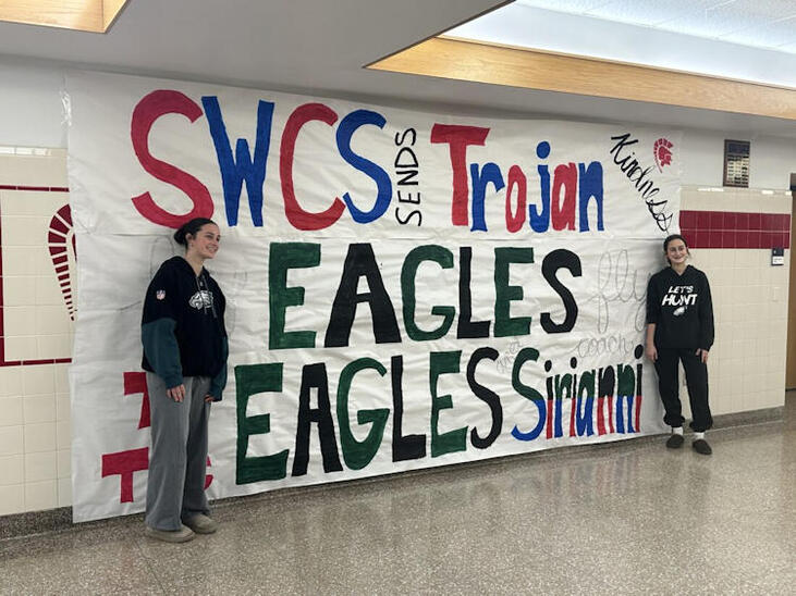Southwestern students wearing Eagles gear are pictured with a banner.